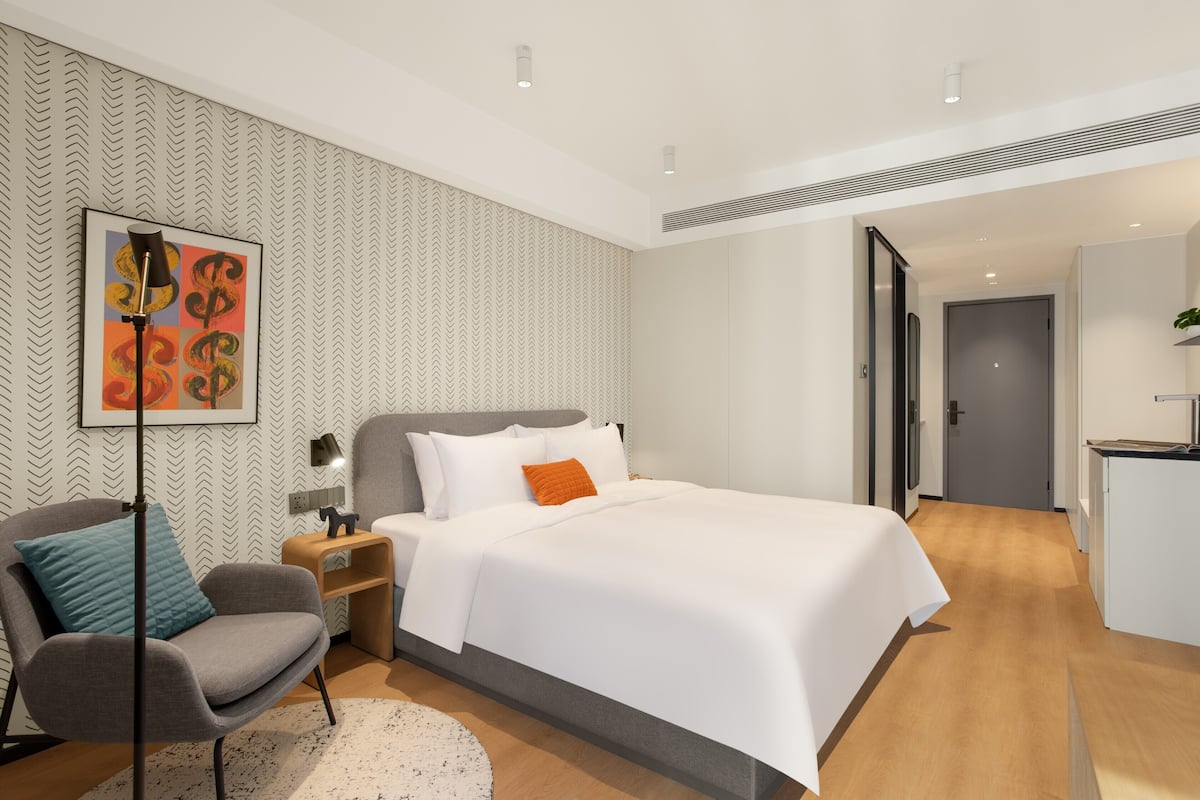 Ein modernes Hotelzimmer mit einem großen Bett, einem Schreibtisch und einem Stuhl.