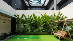 A modern indoor space with artificial grass, a swing, and lush greenery. - Stey-Shenzhen Qianhai Hotel & Apartment (Shenzhen)