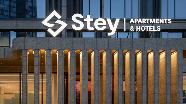 A Stey Apartments & Hotels building facade with a modern design, featuring vertical light strips and a prominent logo. - Stey-Shenzhen Qianhai Hotel & Apartment (Shenzhen)