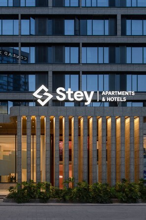 A Stey Apartments & Hotels building facade with a modern design, featuring vertical light strips and a prominent logo. - Stey-Shenzhen Qianhai Hotel & Apartment (Shenzhen)