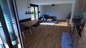A spacious living area with a dining table, chairs, a sofa, and a kitchen area. - Charming Family Apartment in Bürserberg Österreich (Buerserberg)