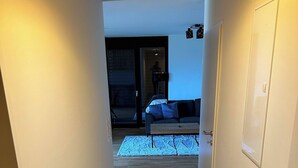 A narrow hallway with wooden flooring leading to a living area with a sofa and a TV. - Charming Family Apartment in Bürserberg Österreich (Buerserberg)