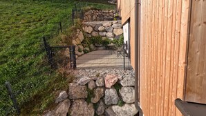 A wooden building with a stone pathway leading to a door, surrounded by a grassy field and trees. - Charming Family Apartment in Bürserberg Österreich (Buerserberg)