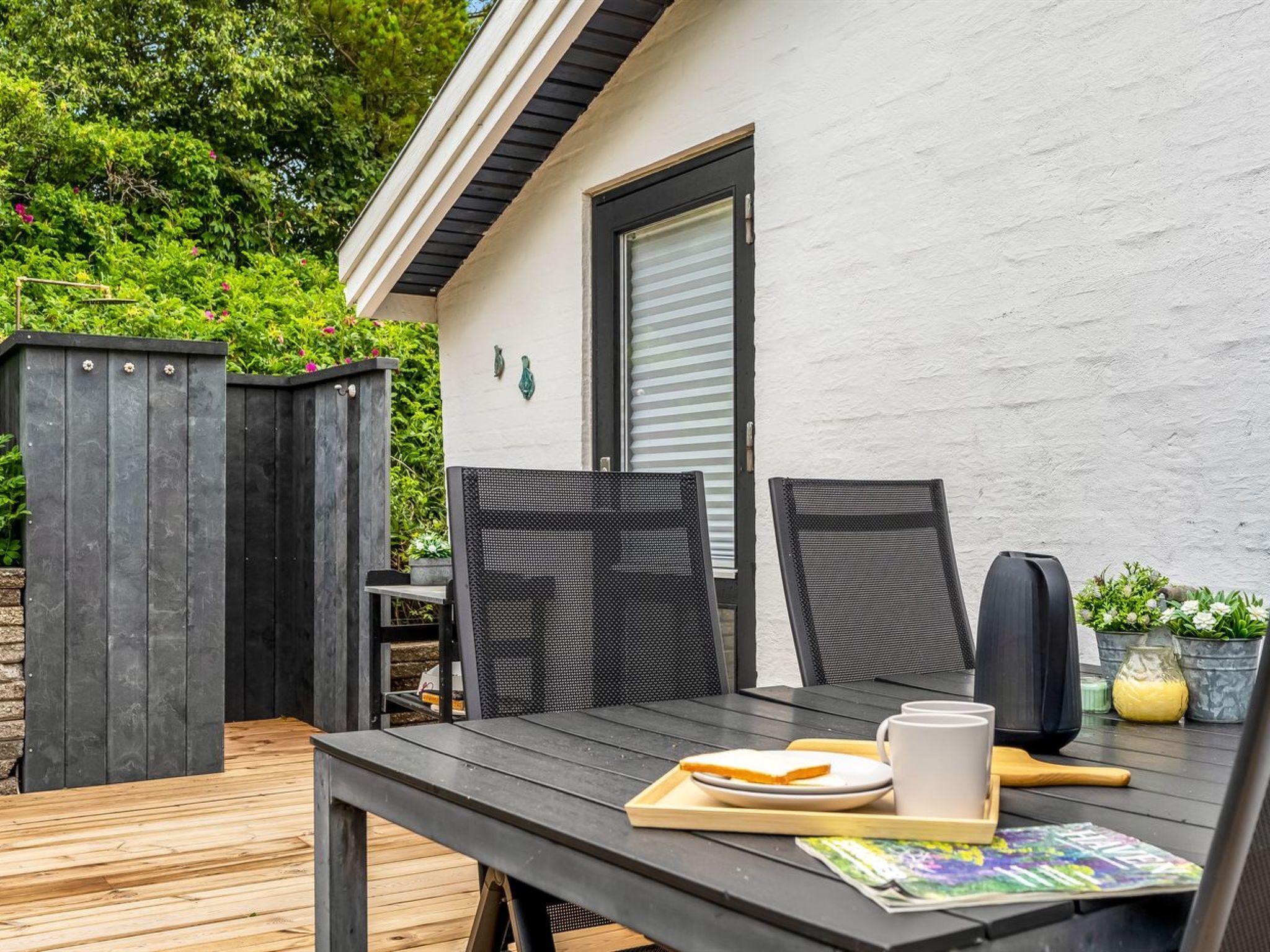 Un patio al aire libre con una mesa, sillas y un pequeño jardín.