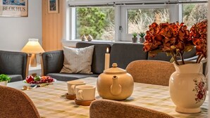 Una sala de estar acogedora con un sofá, una mesa con un set de té, tazas y un florero con flores.