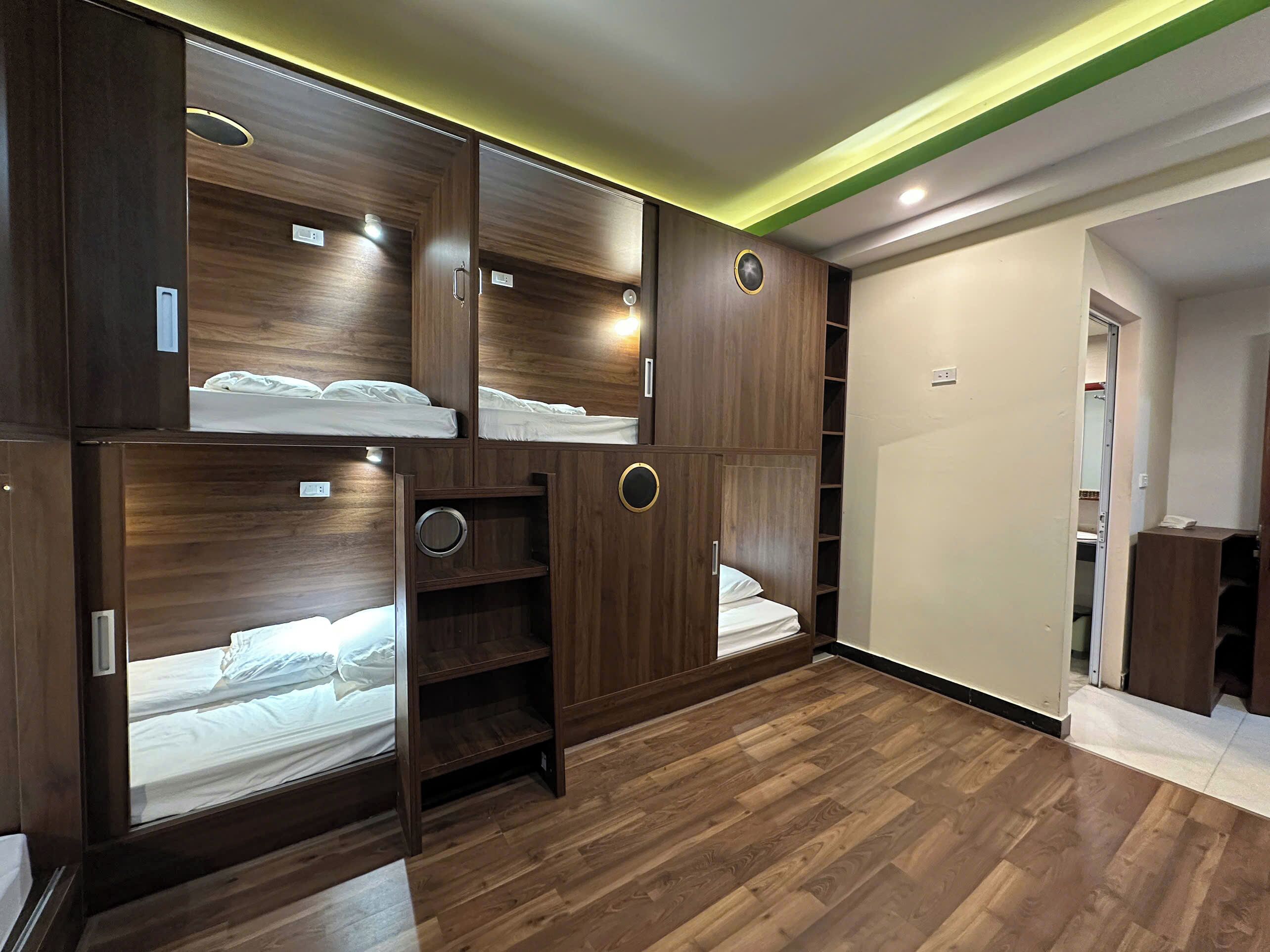 Ein Zimmer mit einem Etagenbett, einem Holzschrank und einer kleinen Regalwand.