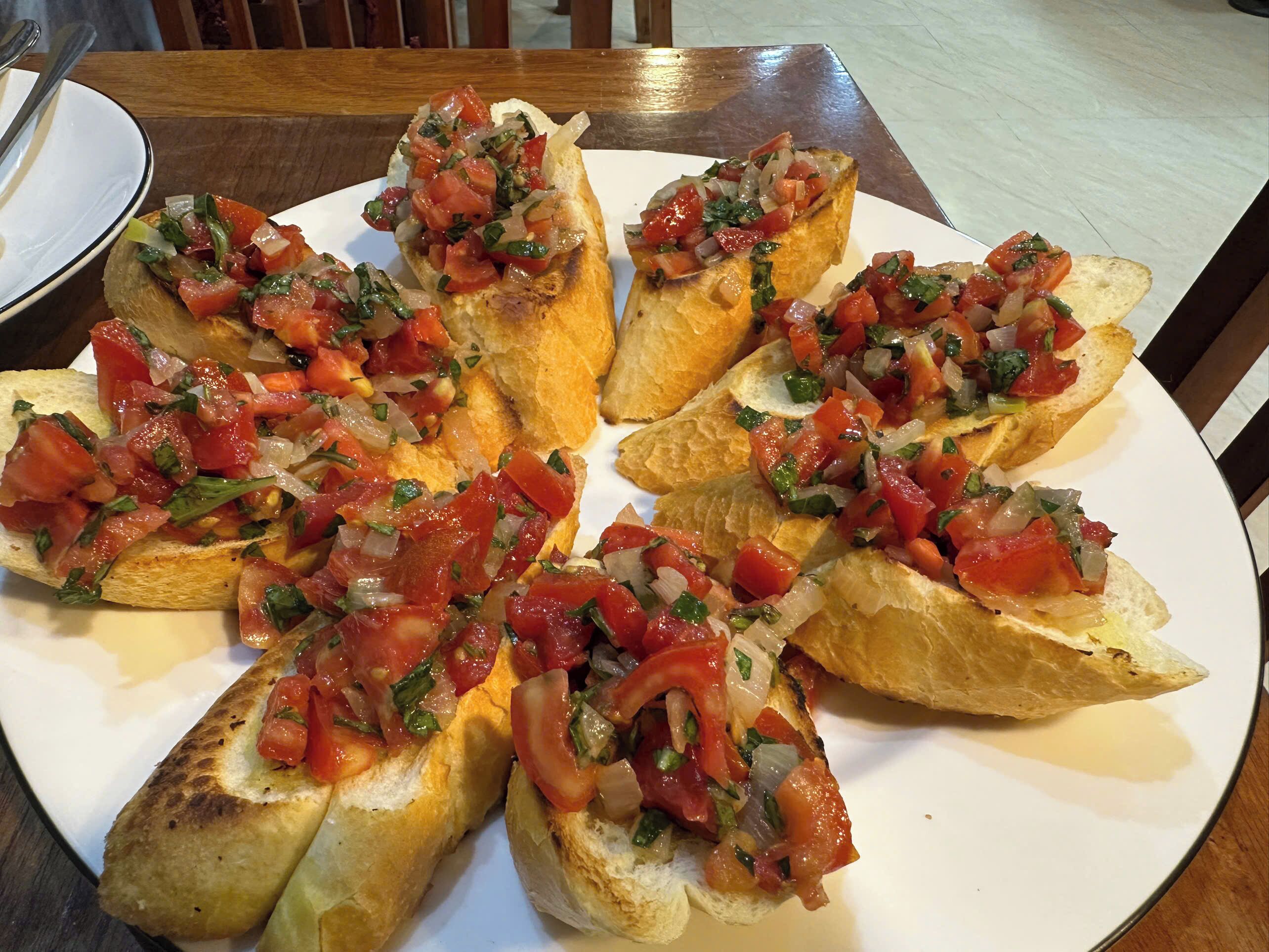 A plate of bruschetta topped with tomatoes and onions.