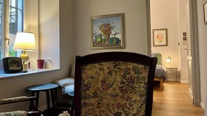 A room with a floral-patterned chair, a small table with a lamp, and a painting on the wall. - Casa Meraviglia Torino (Turin)