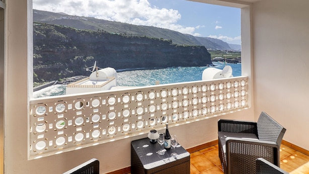 A balcony with a view of a coastal landscape, including cliffs and the sea.