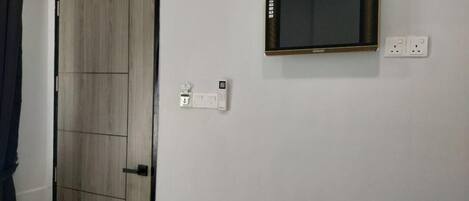 Una habitación con un armario de madera, un televisor de pantalla plana montado y un enchufe.