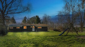 Ein Haus mit geneigtem Dach, einer Veranda und einer Rutsche im Garten.