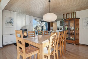 Un coin repas avec une table et des chaises en bois, un luminaire suspendu et un meuble avec des portes en verre.