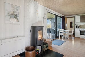 Eine moderne Küche mit Kaminofen, weißen Backsteinwänden und einem Essbereich mit Tisch und Stühlen.