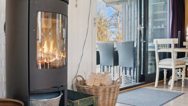 Ein modernes Interieur mit Kaminofen, Korbwannen und einem Essbereich mit Stühlen.