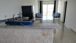 Une cuisine avec un plan de travail en granit, une cuisinière et un évier. On aperçoit une chaise bleue et une chaise blanche à l’arrière-plan.