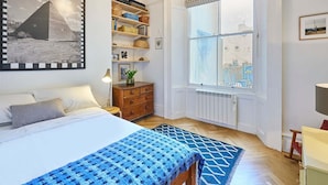 Ett sovrum med en säng, en byrå, ett fönster med utsikt och en hylla med förvaringslådor.