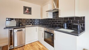 A modern kitchen with white cabinets, black countertops, and stainless steel appliances. - Host Stay Abbey Terrace Apartment (Whitby)