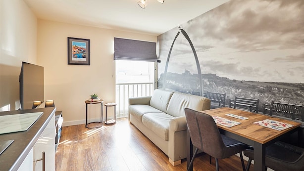 A modern living room with a sofa, dining table, and a cityscape mural. - Host Stay Abbey Terrace Apartment (Whitby)