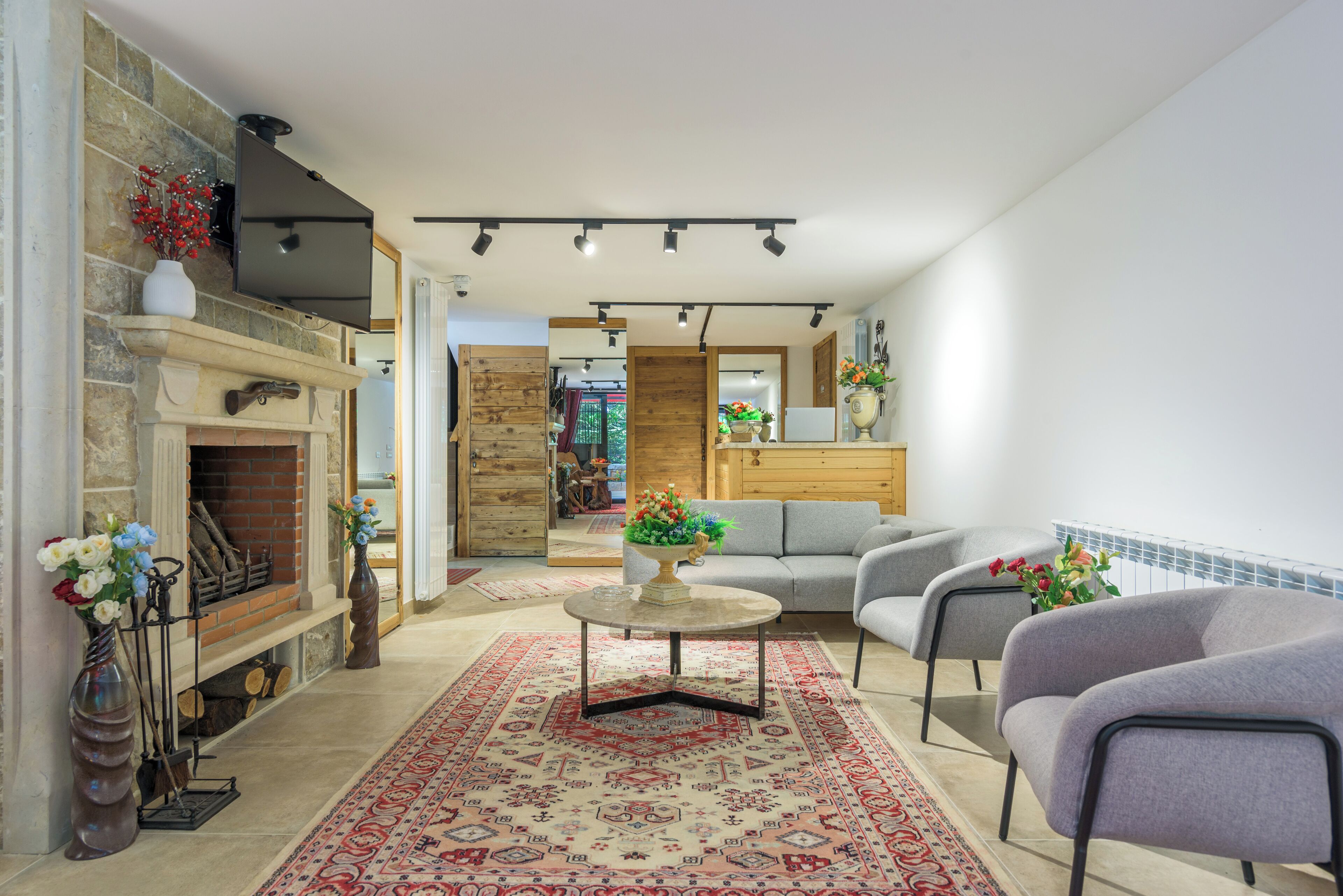 Uma sala de estar com lareira, um sofá, uma mesa de centro e uma televisão na parede.
