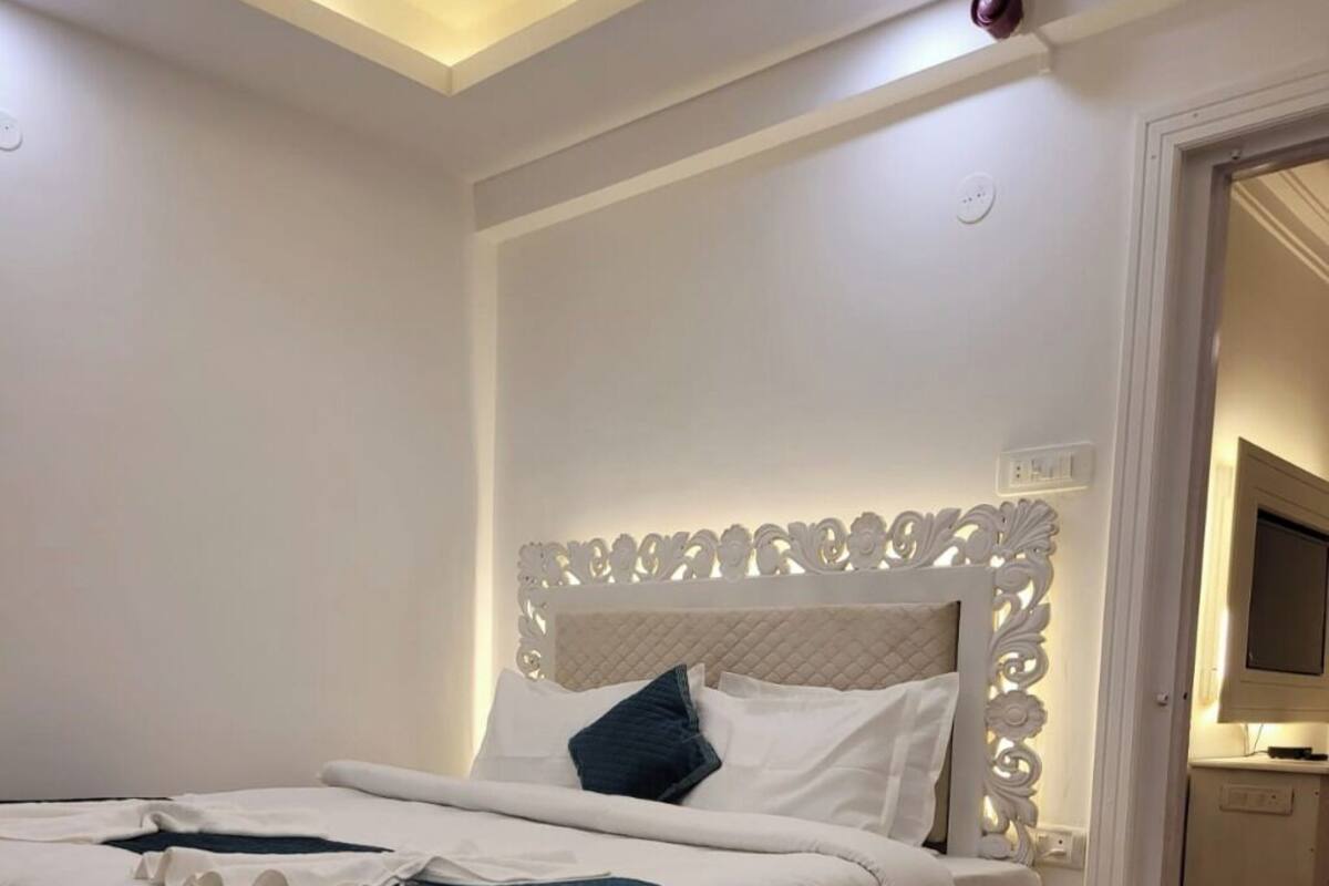 A neatly made bed with a white headboard and a blue throw blanket.