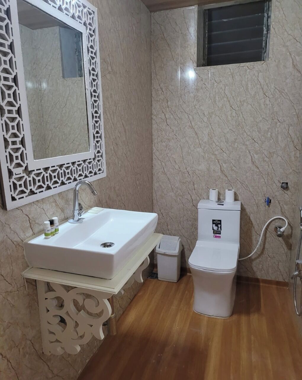 A bathroom with a white sink, a toilet, and a mirror with a decorative frame.