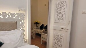 Una habitación de hotel con cama, mesita de noche y puerta con paneles decorativos.