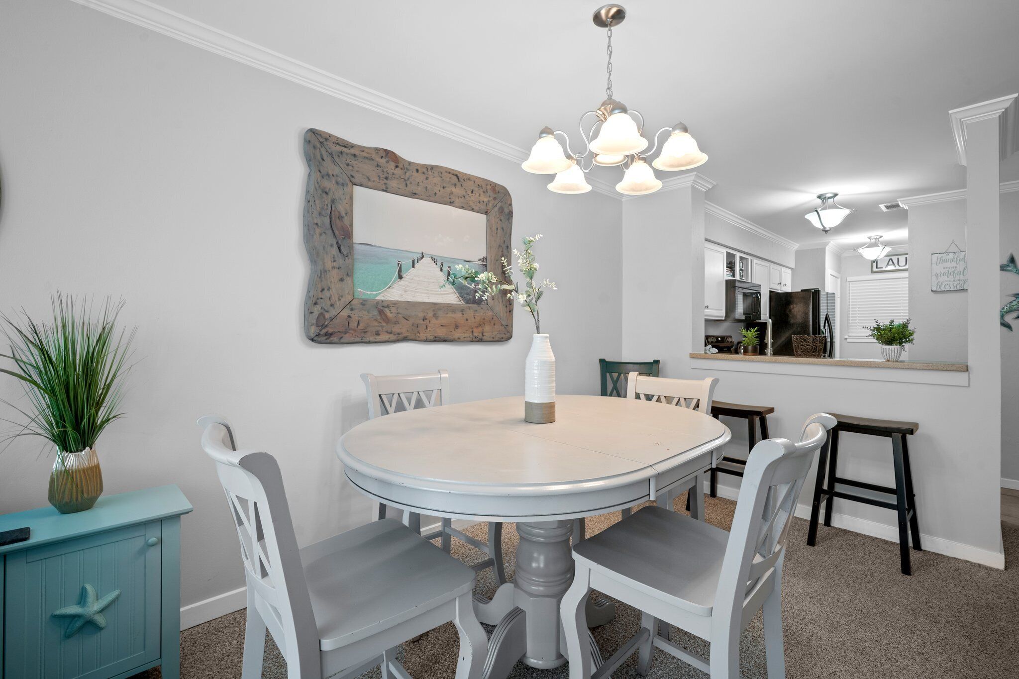 A dining area with a round table, white chairs, a blue cabinet, and a mirror on the wall.
