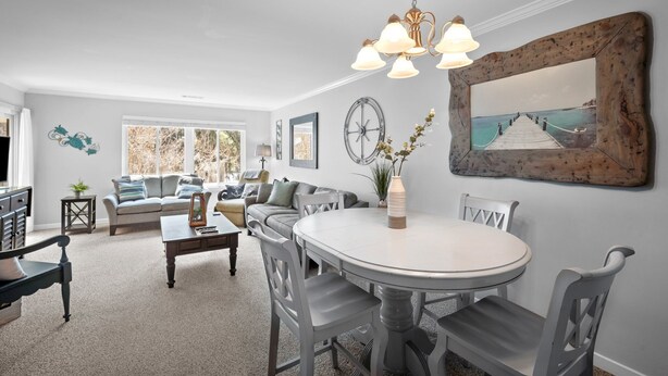 A living room with a round dining table, grey chairs, a sofa, and a chandelier. - Memories are Made Here (Hilton Head Island)