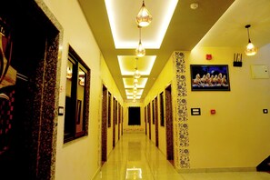 A hotel hallway with a long corridor, patterned walls, and hanging light fixtures. - JMC Hotel RK Inn (Udaipur)