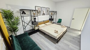 A modern bedroom with a bed, bedside tables, a green chair, a potted plant, and artwork on the wall. - Apartment 'Relax In Der Röntgenstadt' with Wi-Fi (Remscheid)