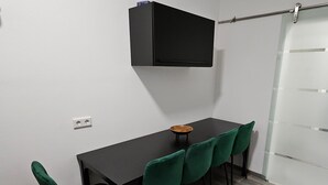 A dining area with a black table, five green chairs, a small wooden bowl, a black cabinet, and a glass partition. - Apartment 'Relax In Der Röntgenstadt' with Wi-Fi (Remscheid)