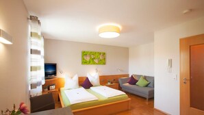 Una habitación de hotel con cama, sofá, televisión y escritorio con silla.
