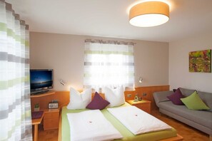 A hotel room with two beds, a TV, a sofa, and a painting on the wall.