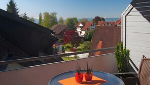Ein Balkon mit Tisch und Stühlen und Blick auf Häuser, der unter einem klaren Himmel liegt.
