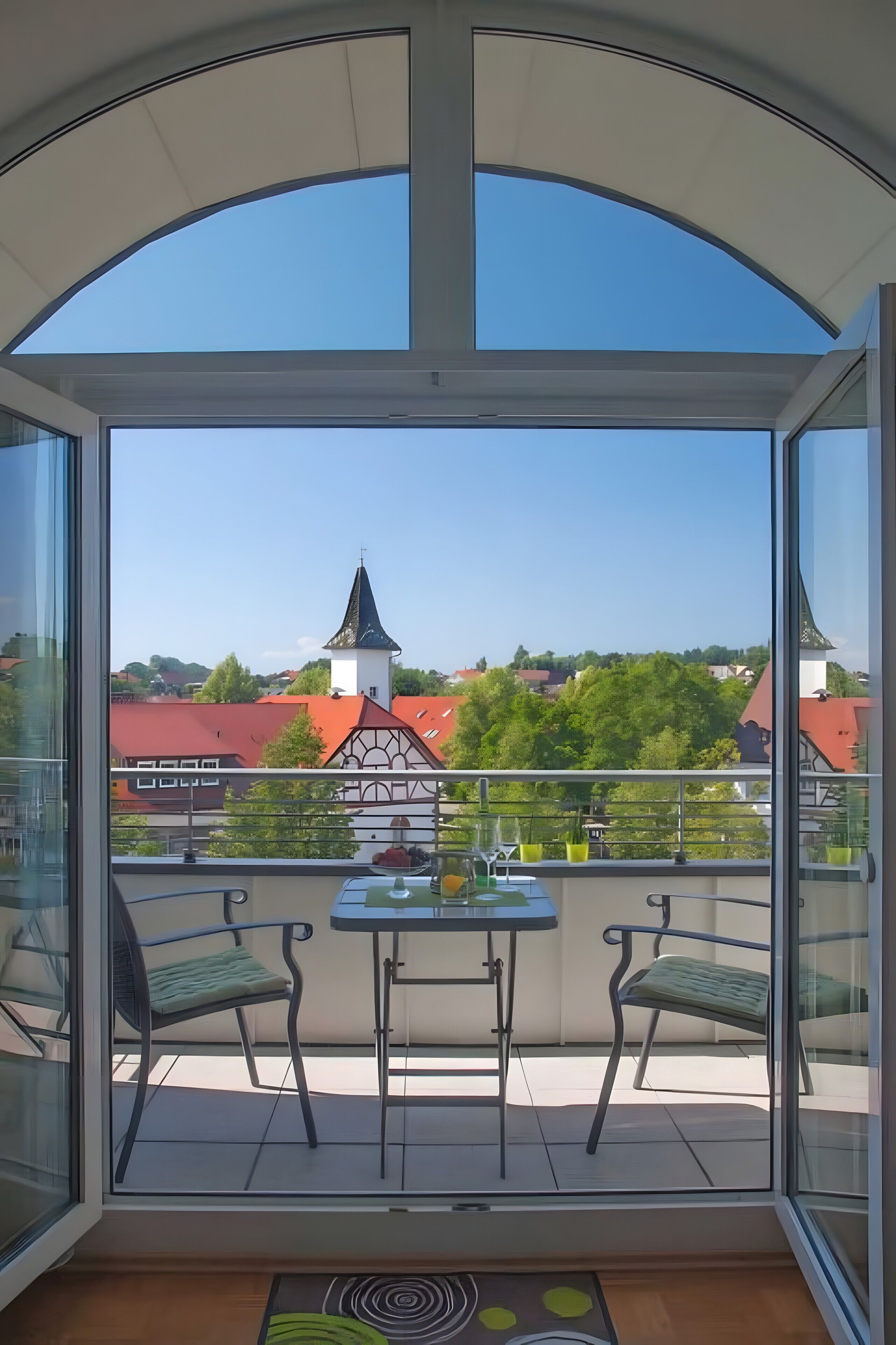 Un balcone con vista panoramica su una città, un tavolo e due sedie.