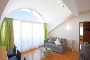 Una habitación con un sofá, una mesa de centro redonda y una zona de comedor con sillas.