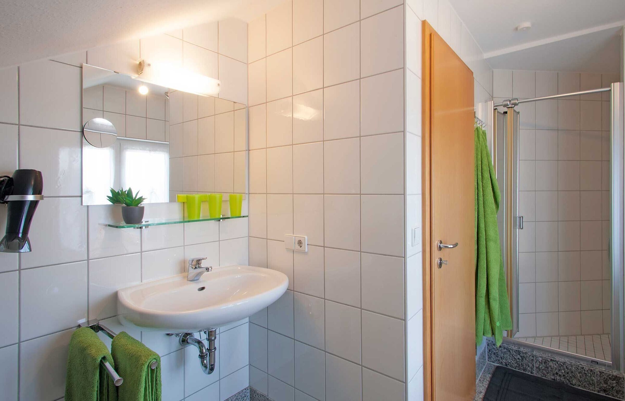 A bathroom with a white sink, mirror, and green towels.