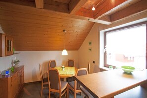 A dining area with a wooden table, chairs, and a window with a view.