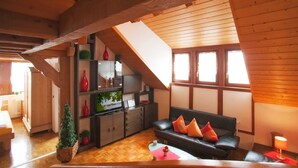 A cozy living room with a wooden ceiling, a black leather sofa, and a television. - Apartment '2' with Balcony and Wi-Fi (Wasserburg (Bodensee))