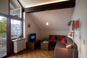 A modern living room with a TV, sofa, and floor lamp. - Apartment '3' with Balcony and Wi-Fi (Wasserburg (Bodensee))