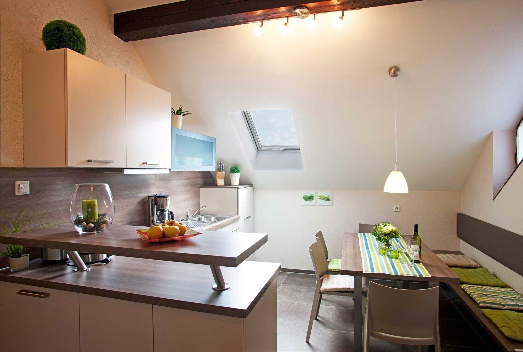 Een moderne keuken met een eethoek, houten balken, een klein raam en een plafondlamp.