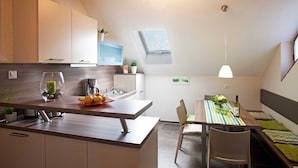 Eine moderne Küche mit Essbereich, Holzbalken, einem kleinen Fenster und einer Deckenleuchte.