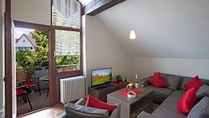 Ein modernes Wohnzimmer mit Fernseher, Sofa und Sesseln.