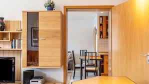 A compact living space with a wooden cabinet, a television, a small table, and a dining area.