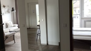 A room with a large mirror, a white sofa, a small table, and a stool.