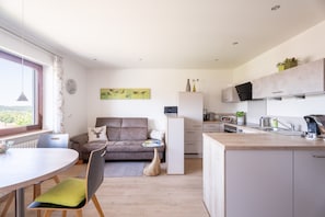 Un espacio moderno para vivir con comedor, sofá, cocina y vistas al exterior.