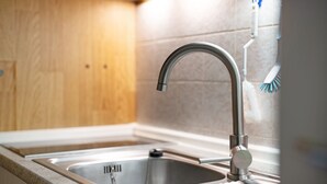 Una cocina moderna con un lavamanos de acero inoxidable, armarios de madera y salpicadero de azulejos.