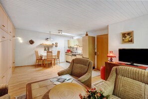 Una sala de estar con sofá, sillón, mesa de comedor y área de cocina.