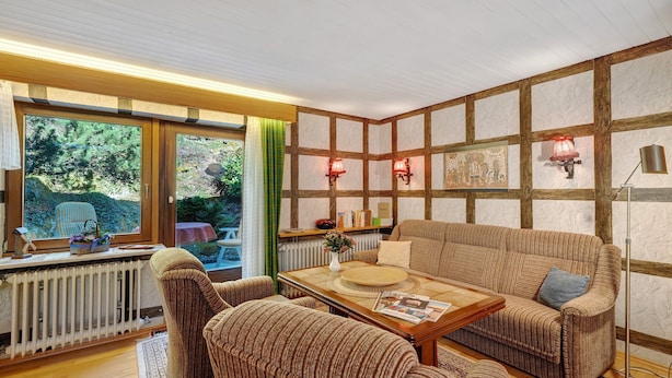A cozy living room with a wooden-framed wall, a sofa, a coffee table, and a radiator. - Studio '3' with Private Terrace, Shared Garden and Wi-Fi (Schönwald im Schwarzwald)