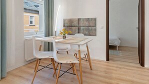 A dining area with a table, chairs, and a view of a building through a window. - Apartment 'Baba' with Wi-Fi in Gera (Gera)